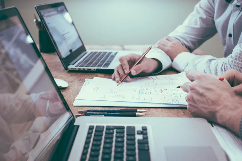 Professionals using laptops and AI tools at a shared work desk