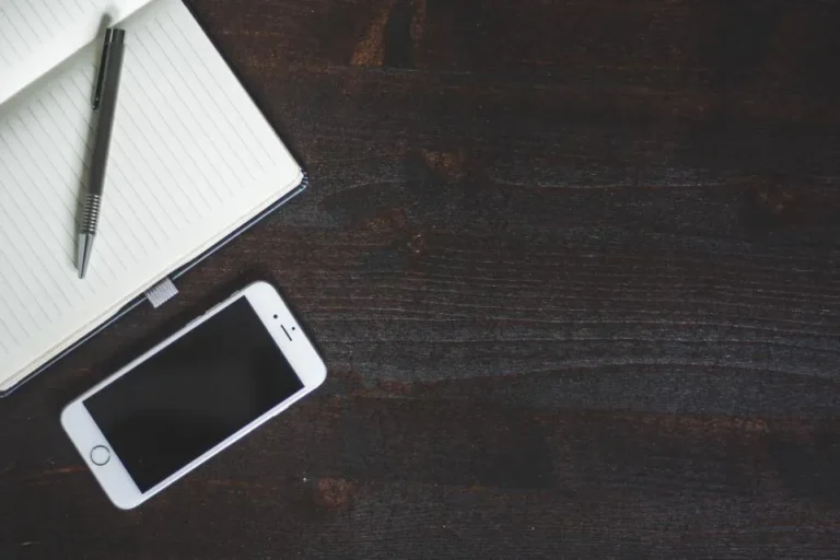 Notebook, pen and smartphone on a desk for contacting Domikyo.com