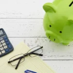 Green piggy bank with calculator and coins for an emergency fund