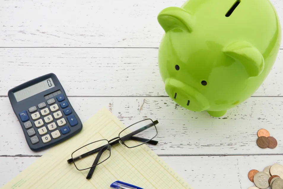 Green piggy bank with calculator and coins for an emergency fund
